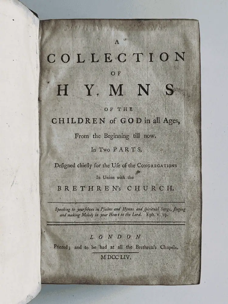 A photo of the cover page of the 1754 English hymnal. It reads: A Collection of Hymns of the Children of God in All Ages, From the Beginning till now. Designed chiefly for the Use of the Congregations in Union with the Brethren’s Church. Speaking to yourselves in Psalms and Hymns and Spiritual Songs, singing and making Melody in your Heart to the Lord. Eph. v19. London. Printed and to be had at all the Brethren's Chapels. MDCCLIV (which is 1754 in Roman Numerals).