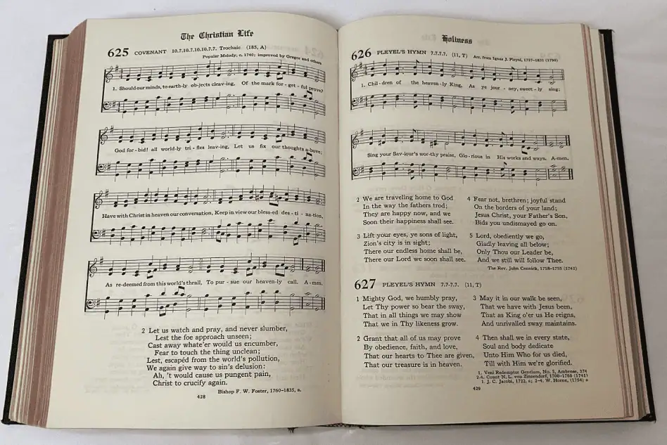 A photo of the black hymnal opened to hymns 625 and 626. The musical stanzas have four part harmony with the lyrics for the first verse in the middle. On the left page is hymn 625. It has a second text only verse below the music. On the right page is hymn 626 at the top. It has four additional verse texts below the music. At the bottom is hymn 627 with four text only verses.