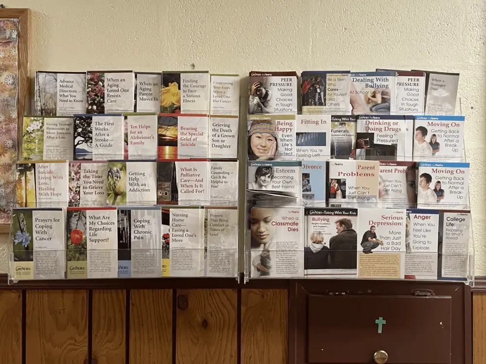 A display case of Care Notes brochures about health and wellness subjects such as "Getting Help with an Addiction", "Coping with Chronic Pain", and "Being Happy Even When Life's Not Perfect".