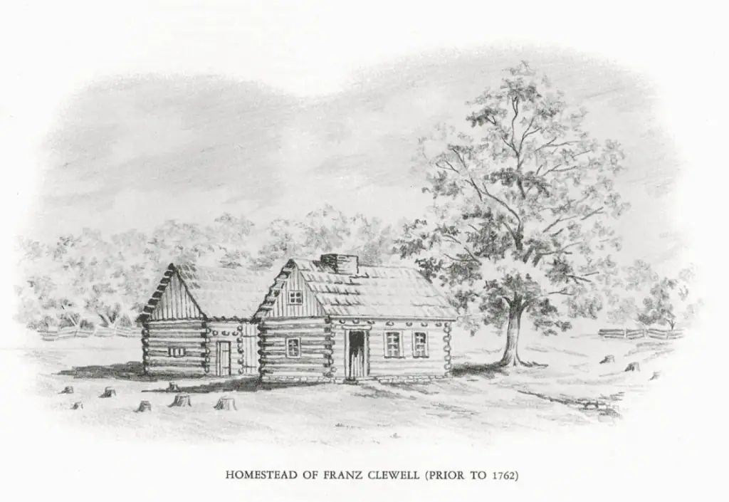 A sepia-toned drawing entitled "Homestead of Franz Clewell (Prior to 1762)". The picture shows two log buildings. There is a small window in the gable and one window on the side with a door and two windows on the front of the building in the foreground. The building behind it is possibly a barn and has one small window on the side and a regular door visible and what may be a barn door just visible to its right on the front.