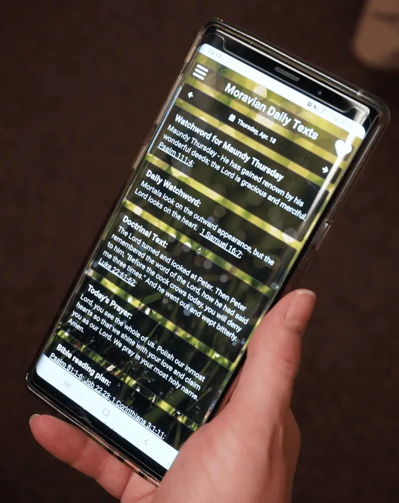 A photo shown holding a cell phone with the Moravian Daily Texts app on the screen.
