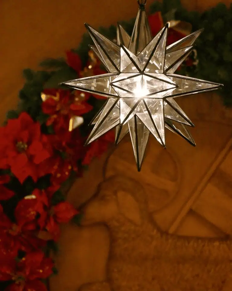 A clear glass Moravian star shines in the sanctuary of First Moravian Church in Dover, Ohio. In the background of the photo you can see festive poinsettia garland decorated their Moravian seal.