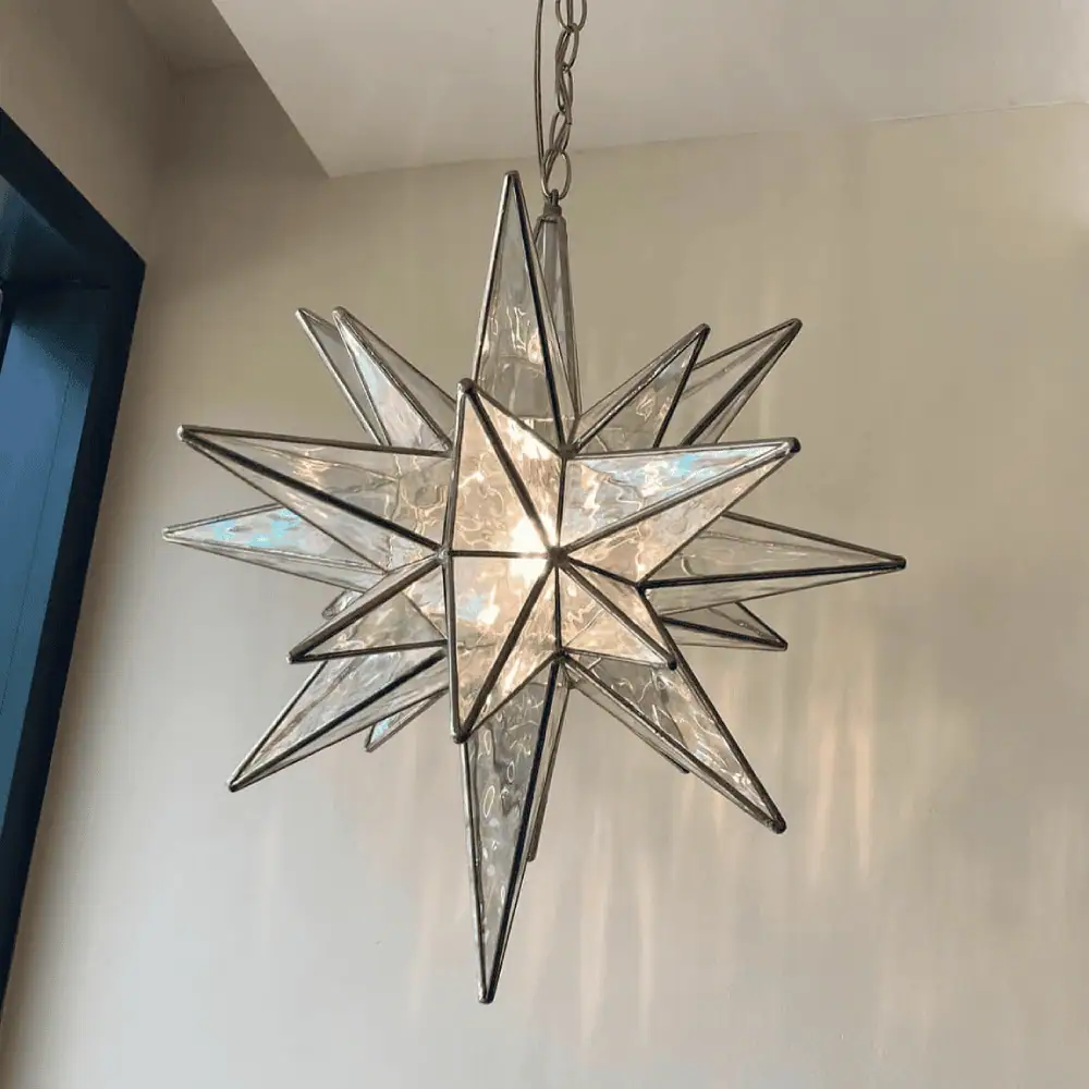 A Moravian star - made of an iridescent clear stained glass - hangs inside a doorway in this photo.
