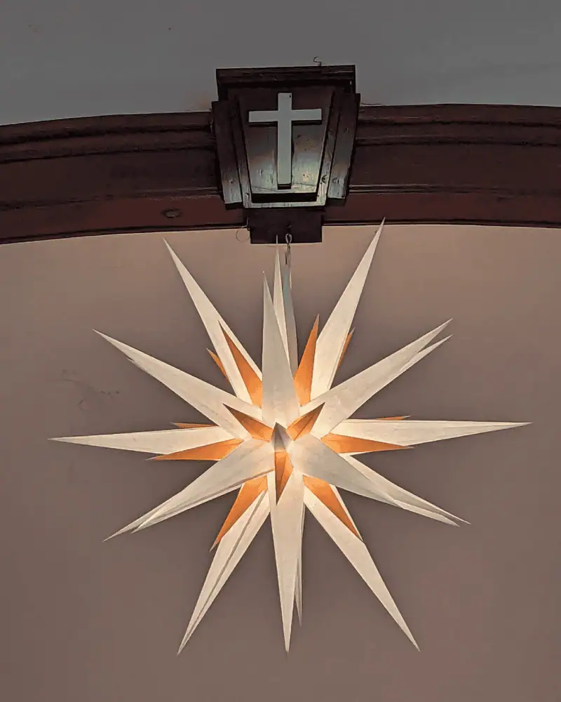A close-up photo of Schoeneck's Moravian Star hanging in the sanctuary. The star is made of white and yellow-orange points.