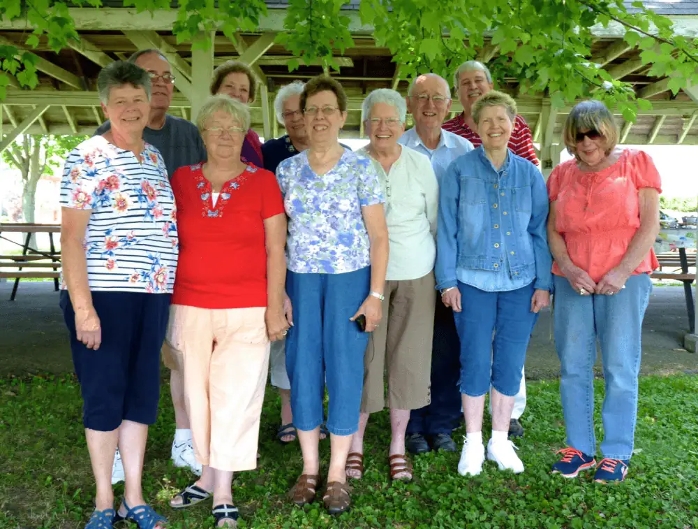 A group of eleven Schoeneckian senior citizens at a fellowship luncheon in the church grove celebrating all of the volunteers who help in the Church Office.