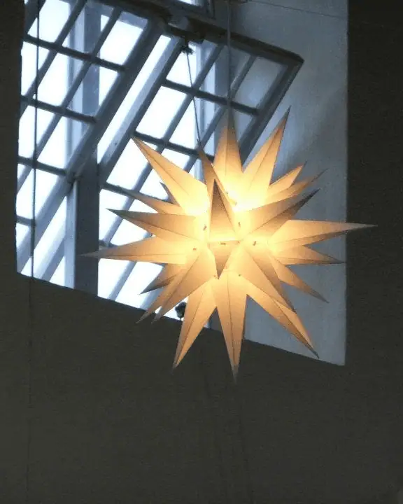 A glowing Moravian star hangs in front of an open window at Sharon Moravian Church in Barbados.