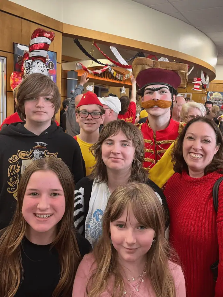 Six Schoeneckian youth and one brave adult stand in the crowded lobby of the local high school theatre after a performance. Two of the youth are still in their performance costumes.