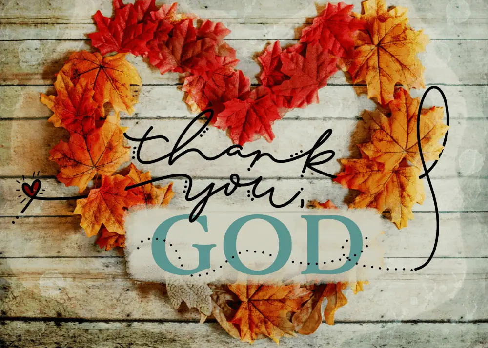 A heart-shaped wreath made of fall leaves in colors of red, orange, and yellow sits upon a rustic wooden background. Inside the heart are the words "Thank You, God."