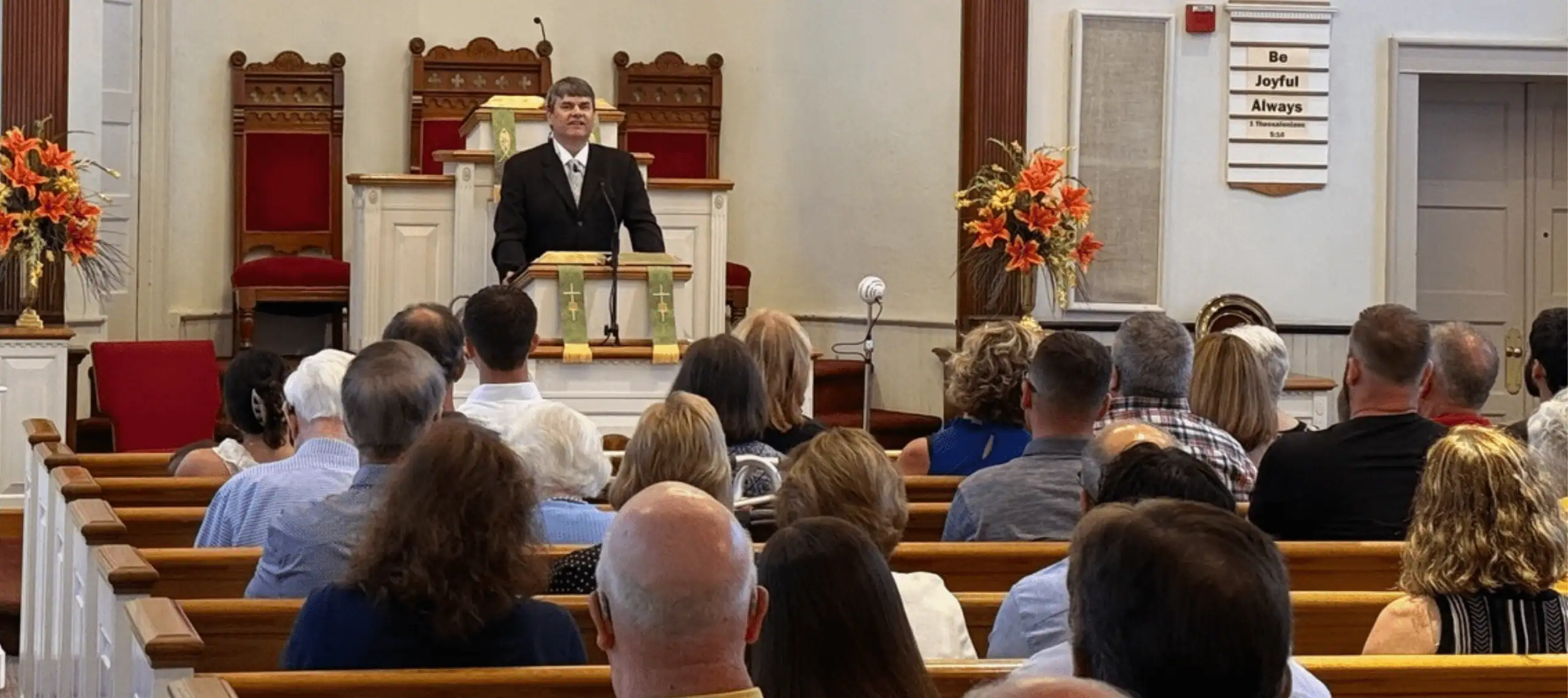 A view of the Schoeneck congregation during worship, with Pastor Ian Edwards preaching, taken from the back of the church.