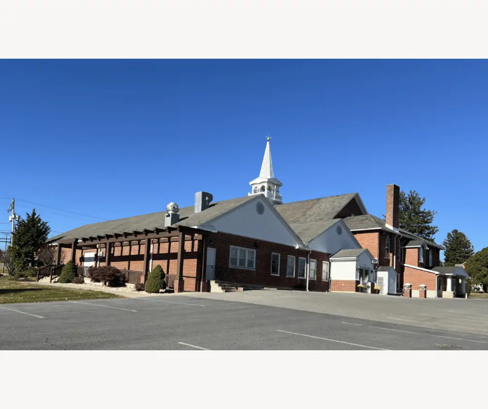 A view of the church building from the lower parking lot on a bright sunny day under a blue sky. Along the side of the church is the pergola outside the Fellowship Hall. A view of the church building from the lower parking lot on a bright sunny day under a blue sky. Along the side of the church is the pergola outside the Fellowship Hall.