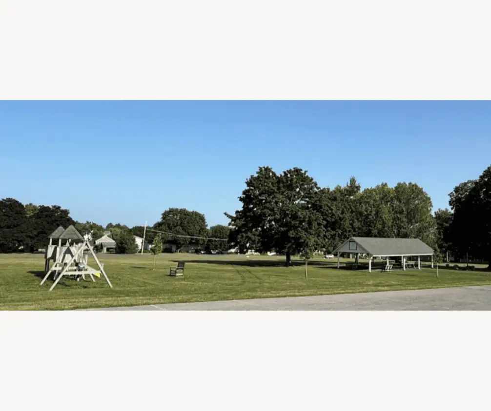 A picture of the Grove on a sunny day. The picture includes the children's play area and the pavilion, along with the field behind it. A picture of the Grove on a sunny day. The picture includes the children's play area and the pavilion, along with the field behind it.
