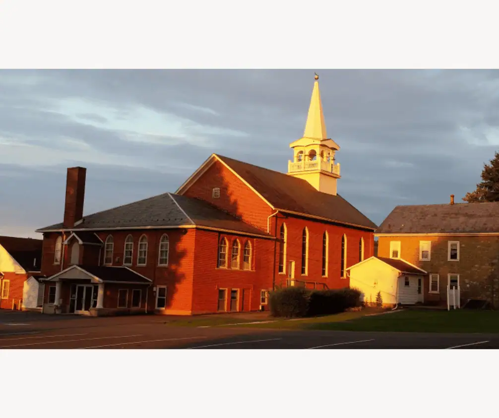 In this photo, the brick edifice of the church is visible. The church sanctuary building can be seen towards the top of the photo, followed by the 1916 Sunday School addition, and the 2007 main entrance addition. To the church's right is the stone parsonage, with the white-sided addition for the kitchen. The empty parking lot is in the foreground of the picture. In this photo, the brick edifice of the church is visible. The church sanctuary building can be seen towards the top of the photo, followed by the 1916 Sunday School addition, and the 2007 main entrance addition. To the church's right is the stone parsonage, with the white-sided addition for the kitchen. The empty parking lot is in the foreground of the picture.
