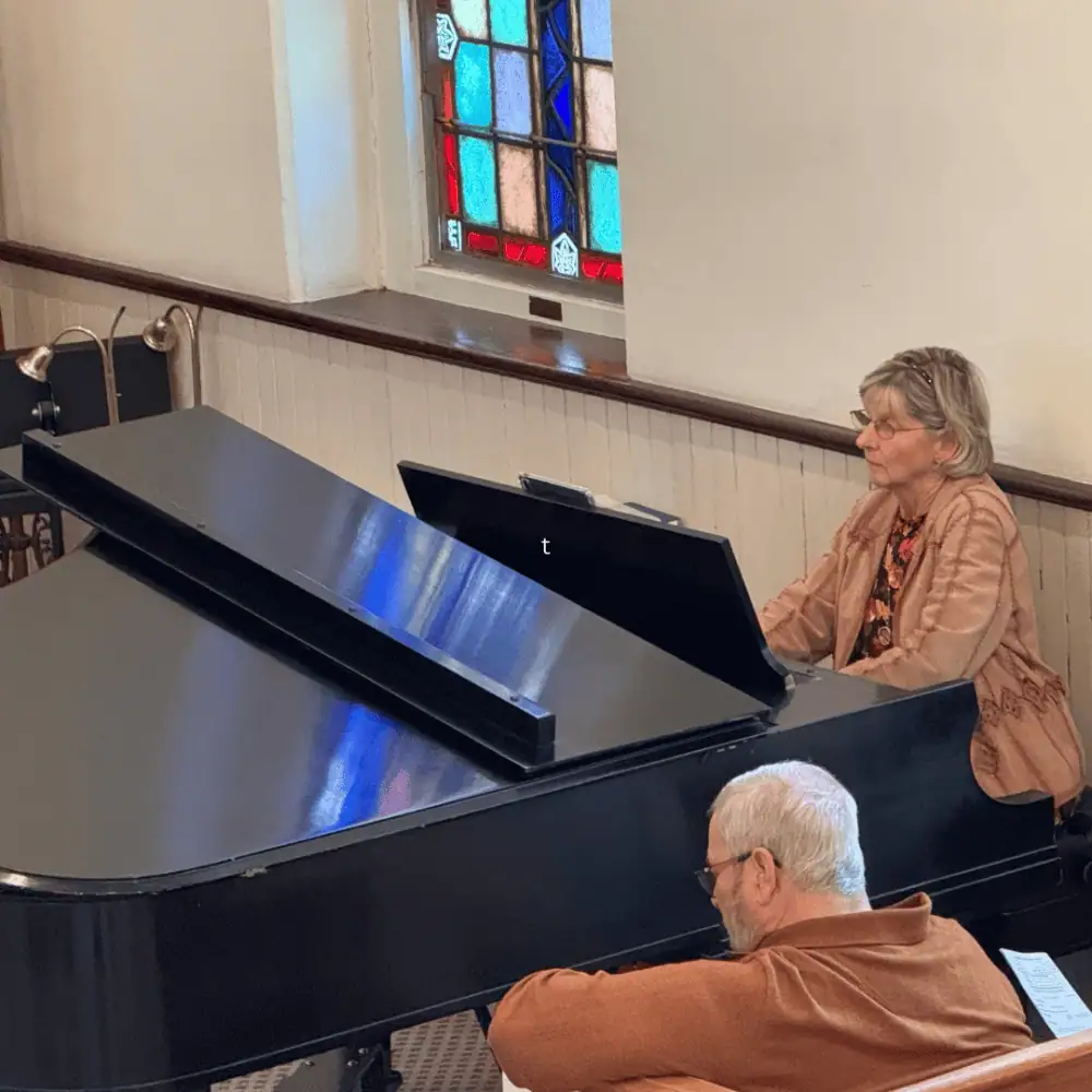 A woman plays the black grand piano in the sanctuary during a worship service.