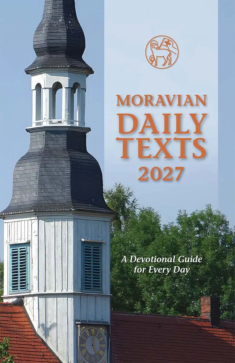 An image of the cover of the 2027 Moravian Daily Texts printed by the IBOC for the American provinces. The cover features the steeple of the Lutheran Church of Berthelsdorf in Herrnhut against a blue sky. This church is the site of the spiritual renewal of the Moravian Church on August 13, 1727. The words “Moravian Daily Texts 2027” is written on a pale blue vertical see-through banner in orange lettering.